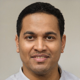 Joyful latino young-adult male with short  black hair and brown eyes