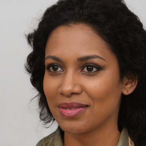 Joyful black young-adult female with long  brown hair and brown eyes