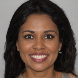 Joyful black young-adult female with long  brown hair and brown eyes