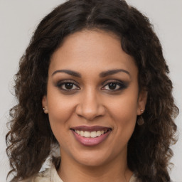 Joyful black young-adult female with long  brown hair and brown eyes