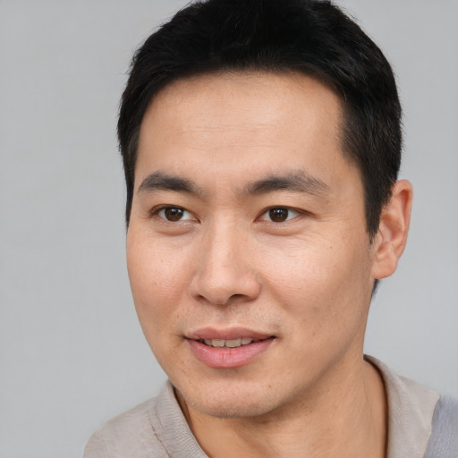 Joyful asian young-adult male with short  black hair and brown eyes