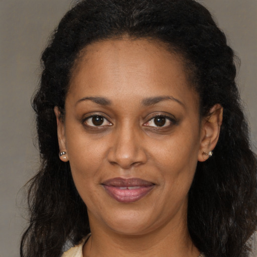 Joyful black adult female with long  brown hair and brown eyes