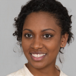 Joyful black young-adult female with long  brown hair and brown eyes