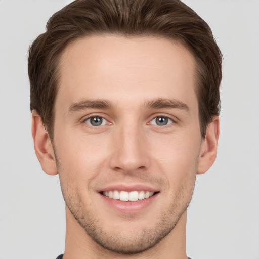 Joyful white young-adult male with short  brown hair and grey eyes