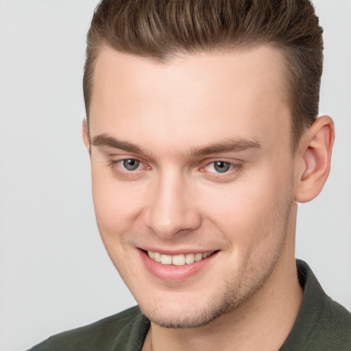 Joyful white young-adult male with short  brown hair and grey eyes