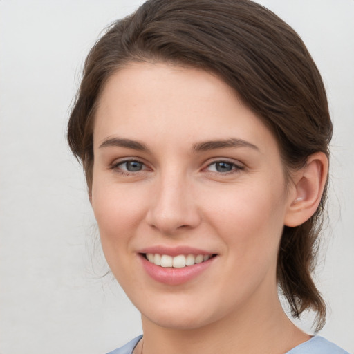 Joyful white young-adult female with medium  brown hair and grey eyes