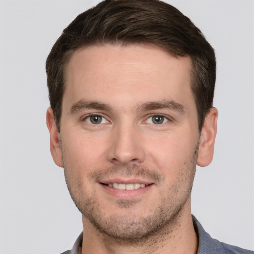 Joyful white young-adult male with short  brown hair and grey eyes