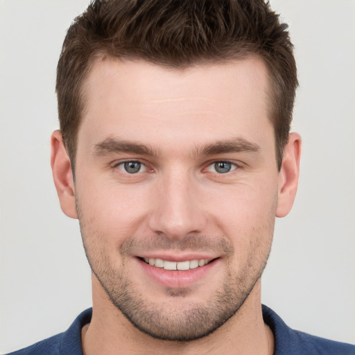 Joyful white young-adult male with short  brown hair and grey eyes