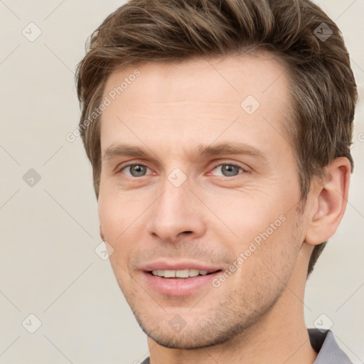 Joyful white young-adult male with short  brown hair and grey eyes