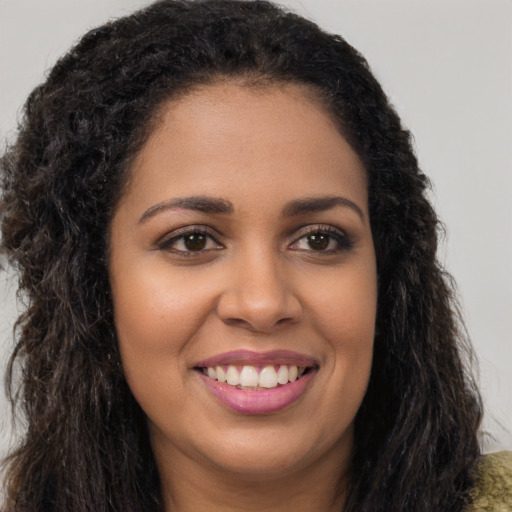 Joyful black young-adult female with long  brown hair and brown eyes