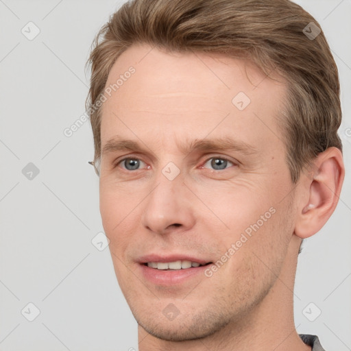 Joyful white young-adult male with short  brown hair and grey eyes