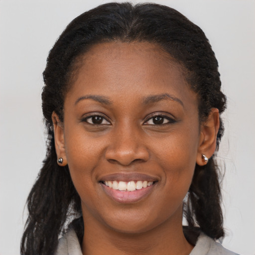 Joyful black young-adult female with long  brown hair and brown eyes