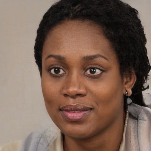 Joyful black young-adult female with long  black hair and brown eyes
