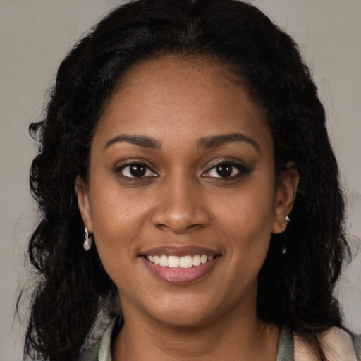 Joyful black young-adult female with long  brown hair and brown eyes