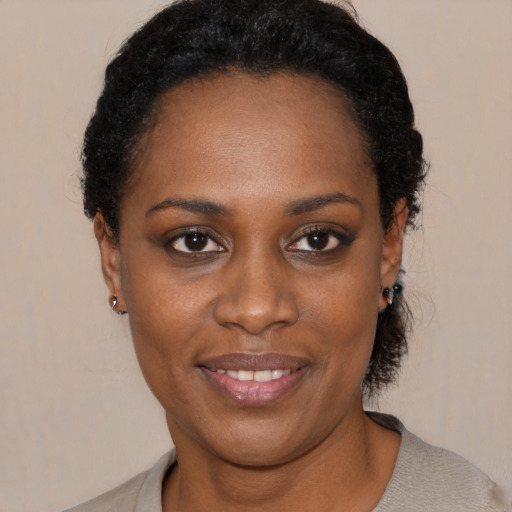 Joyful black young-adult female with short  black hair and brown eyes