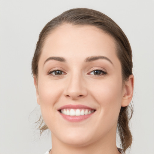 Joyful white young-adult female with medium  brown hair and grey eyes