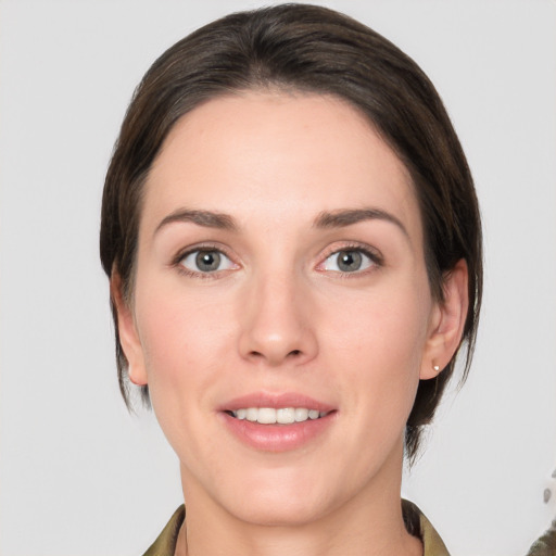 Joyful white young-adult female with medium  brown hair and grey eyes