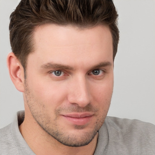 Joyful white young-adult male with short  brown hair and grey eyes