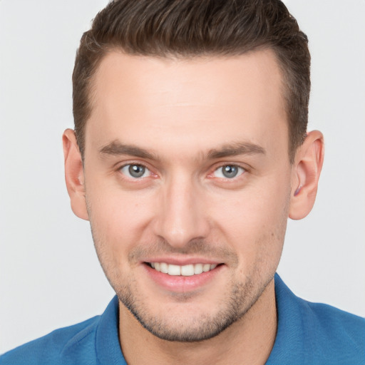 Joyful white young-adult male with short  brown hair and grey eyes