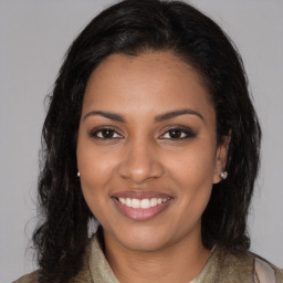 Joyful black young-adult female with long  brown hair and brown eyes