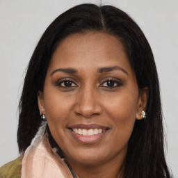 Joyful black adult female with long  brown hair and brown eyes