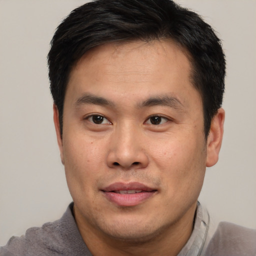 Joyful asian young-adult male with short  brown hair and brown eyes