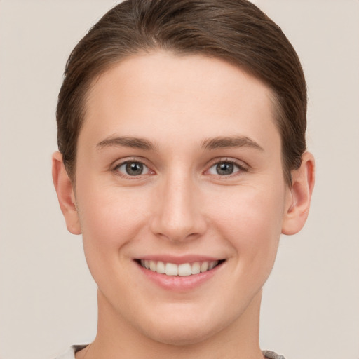 Joyful white young-adult female with short  brown hair and grey eyes