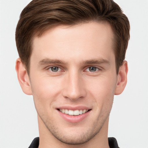 Joyful white young-adult male with short  brown hair and grey eyes