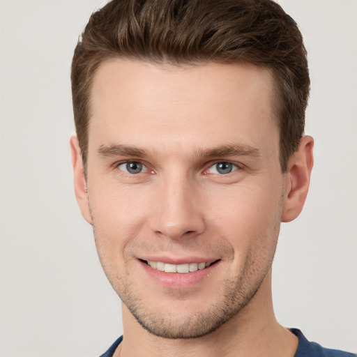 Joyful white young-adult male with short  brown hair and grey eyes