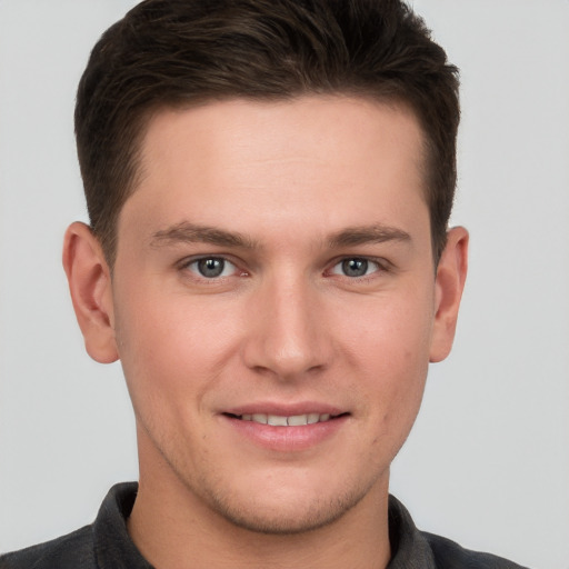 Joyful white young-adult male with short  brown hair and grey eyes