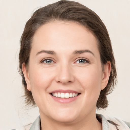 Joyful white young-adult female with medium  brown hair and grey eyes