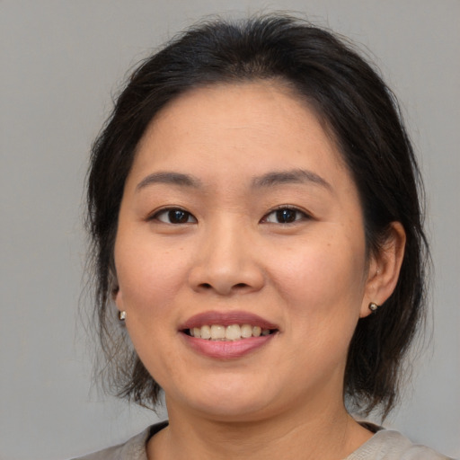 Joyful asian young-adult female with medium  brown hair and brown eyes