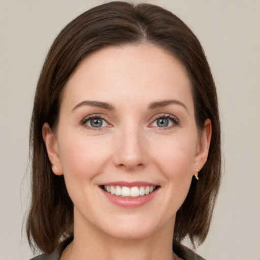 Joyful white young-adult female with medium  brown hair and grey eyes