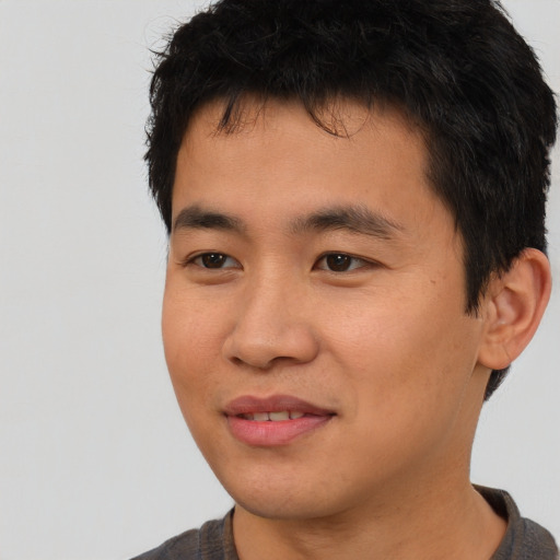 Joyful asian young-adult male with short  brown hair and brown eyes