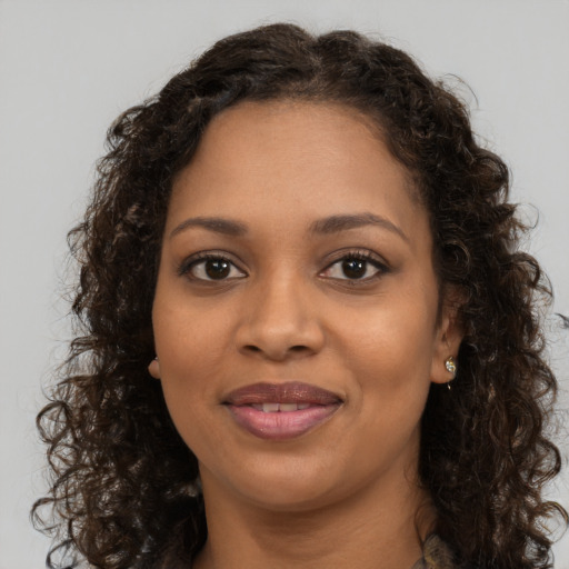 Joyful black young-adult female with long  brown hair and brown eyes