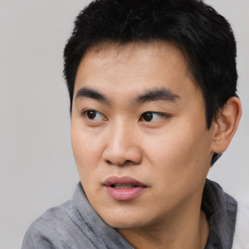Joyful asian young-adult male with short  black hair and brown eyes