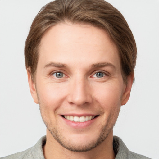 Joyful white young-adult male with short  brown hair and grey eyes