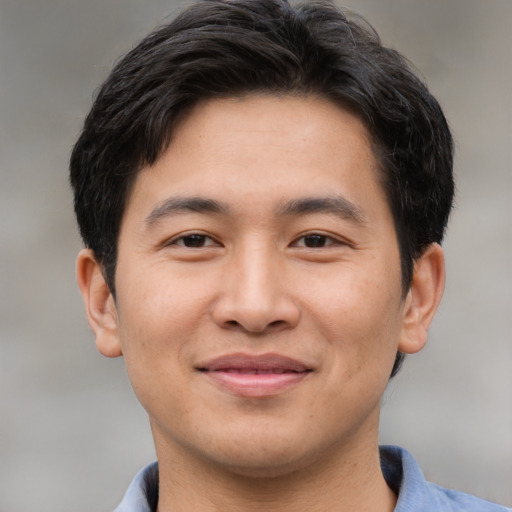 Joyful asian young-adult male with short  brown hair and brown eyes