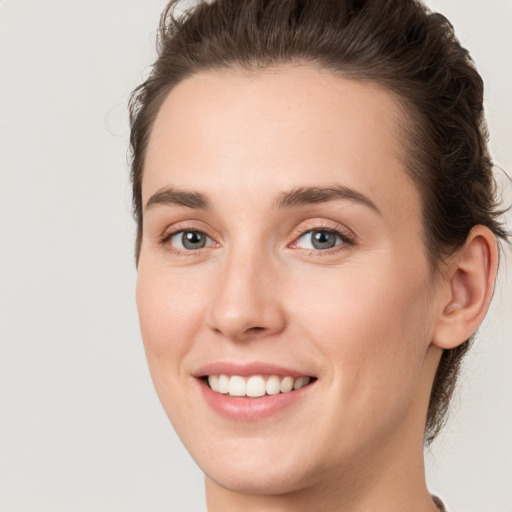 Joyful white young-adult female with medium  brown hair and grey eyes