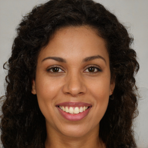Joyful black young-adult female with long  brown hair and brown eyes