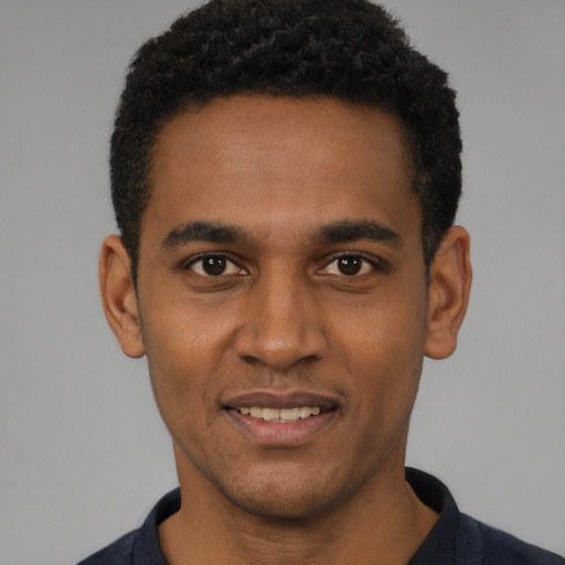 Joyful black young-adult male with short  black hair and brown eyes