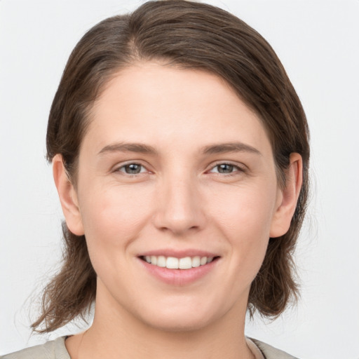 Joyful white young-adult female with medium  brown hair and grey eyes