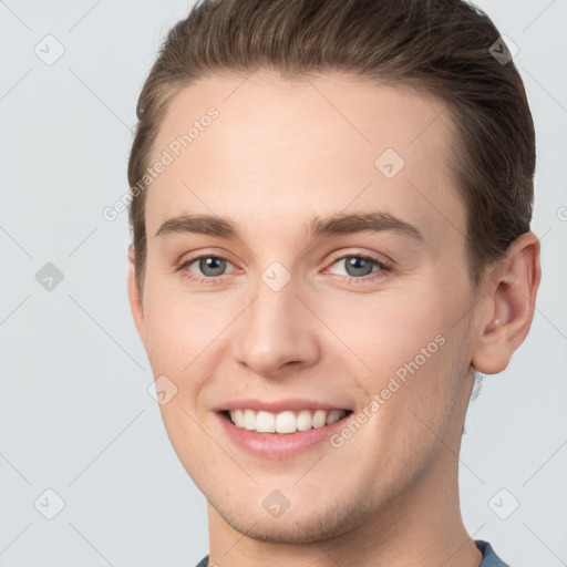 Joyful white young-adult male with short  brown hair and grey eyes