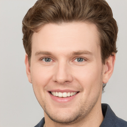 Joyful white young-adult male with short  brown hair and grey eyes