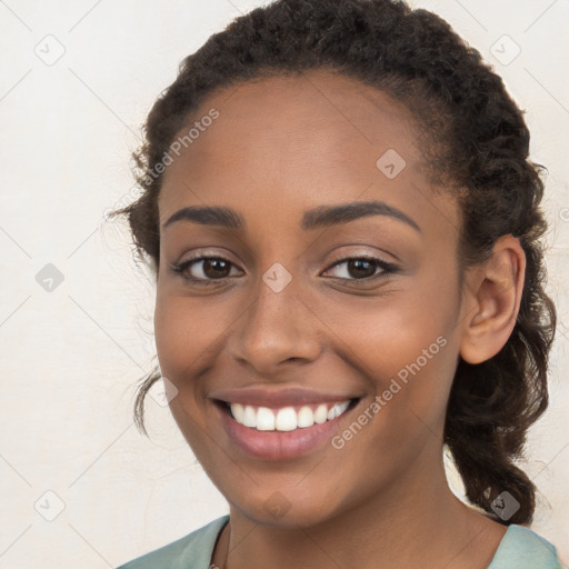 Joyful black young-adult female with long  brown hair and brown eyes