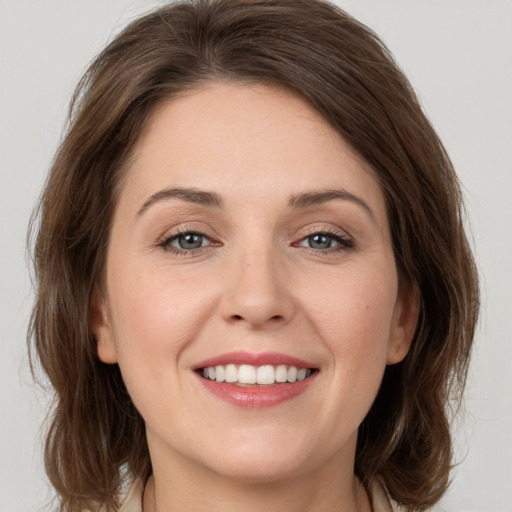 Joyful white young-adult female with medium  brown hair and grey eyes