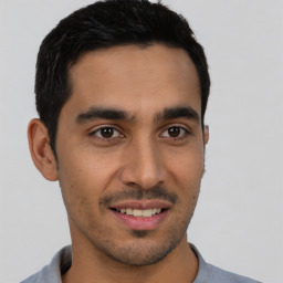 Joyful latino young-adult male with short  brown hair and brown eyes