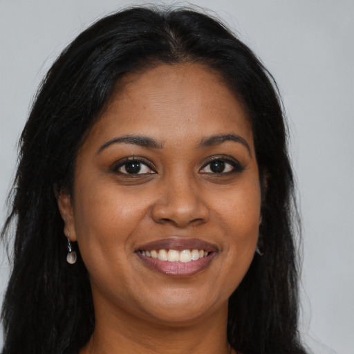 Joyful black young-adult female with long  brown hair and brown eyes