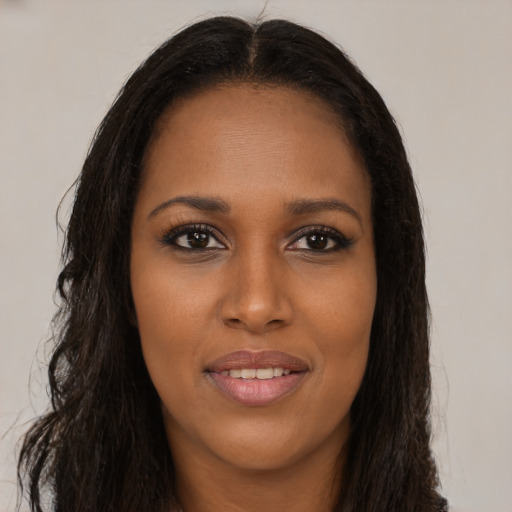 Joyful black young-adult female with long  brown hair and brown eyes