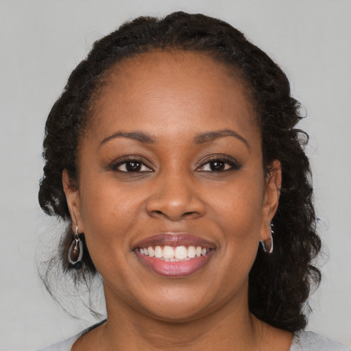 Joyful black young-adult female with long  brown hair and brown eyes